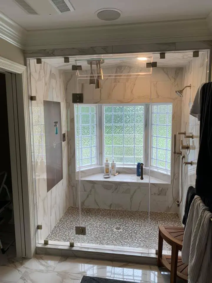 Finished primary bathroom with glass shower and marble-look tile